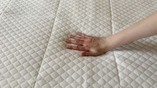 Tester's hand on the cooling cover of the Nectar Hybrid mattress