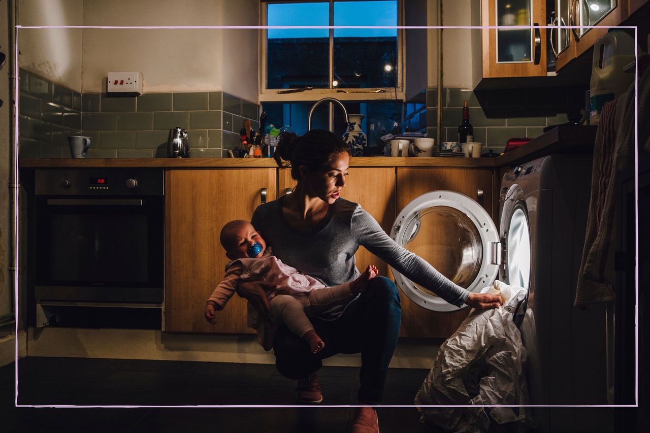 A mother putting a wash on while holding a baby