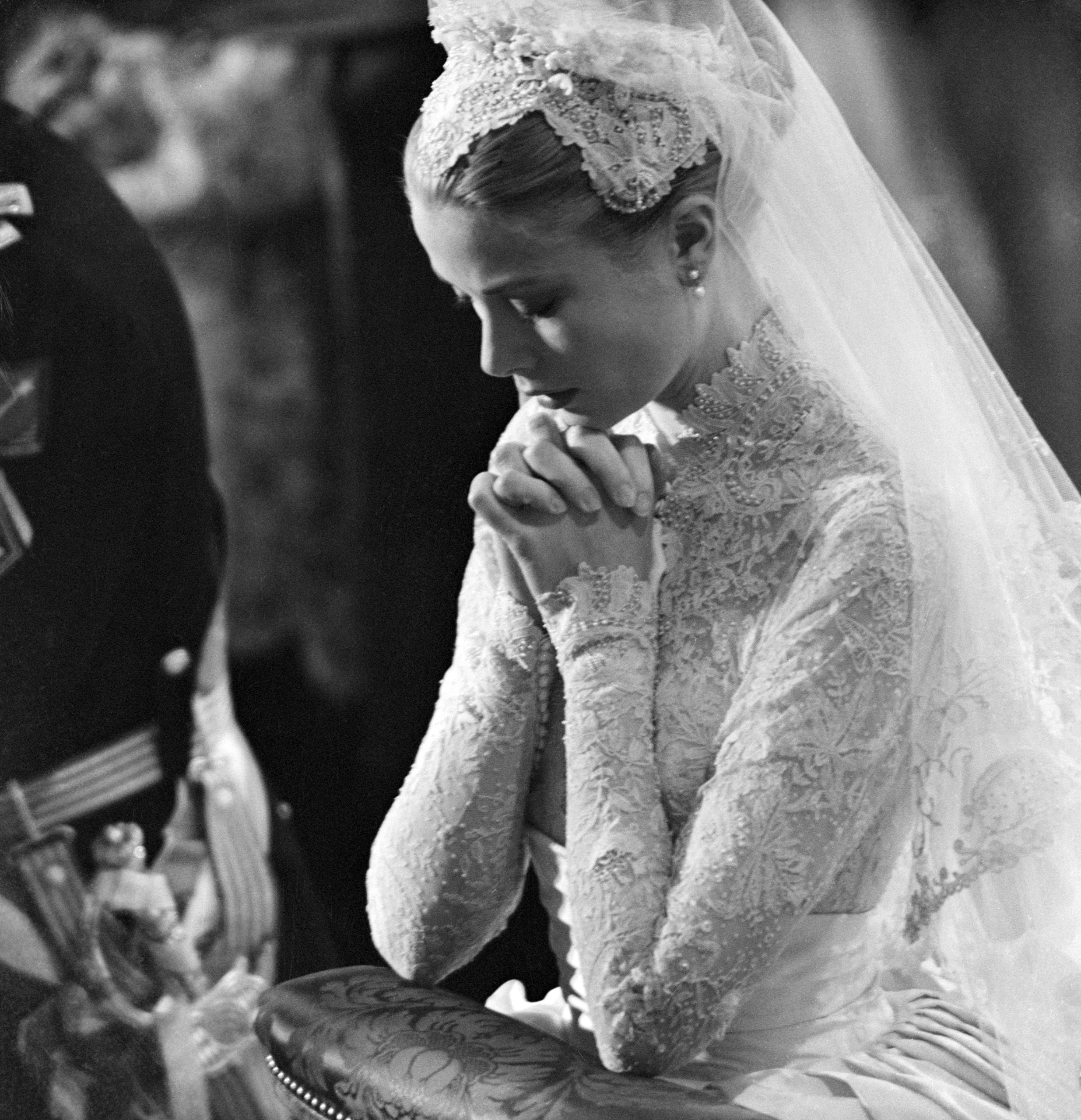 Grace Kelly praying on her wedding day in a lace wedding dress and veil