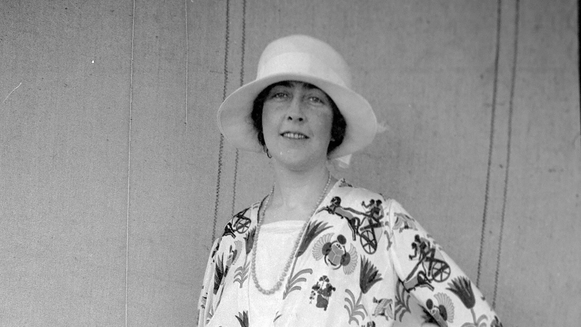 A black and white photo of Agatha Christie with a white hat.