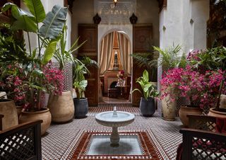 A riad courtyard at Royal Mansour Marrakech with a fountain and pink flowers