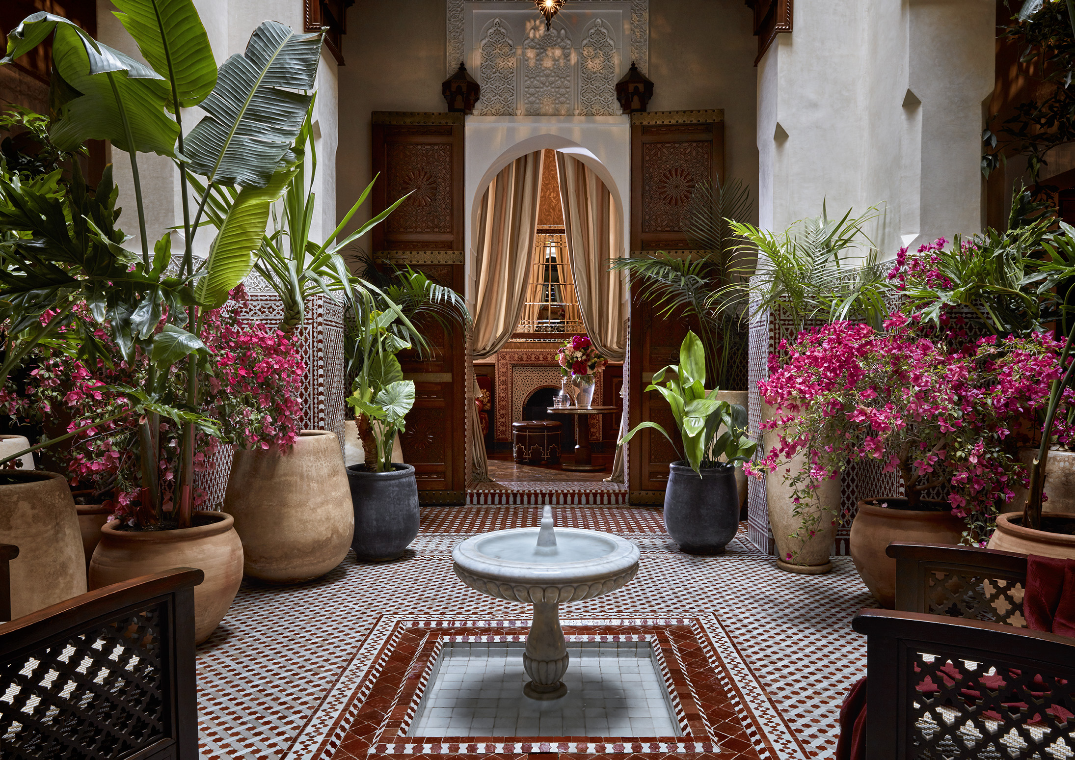 A riad courtyard at Royal Mansour Marrakech with a fountain and pink flowers