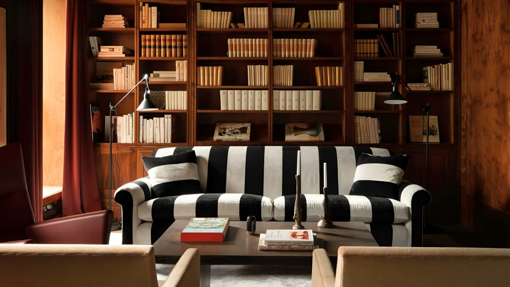 A dark wood living room with floor to ceiling bookshelves. A black and white stripped couch in front of them. 