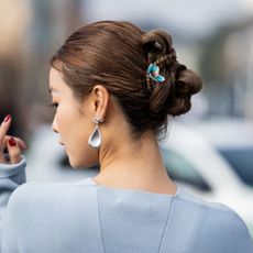 fashion week guest wearing summer hairstyles of braided bun and hair clip GettyImages-2202171475