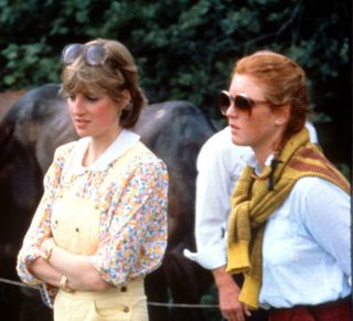 Lady Diana Spencer, wearing yellow dungarees with a floral blouse and red wedges, and Sarah Ferguson attend a polo match at Cowdray Park Polo Club in Gloucestershire, 12th July 1981. (Photo by Anwar Hussein/Getty Images)