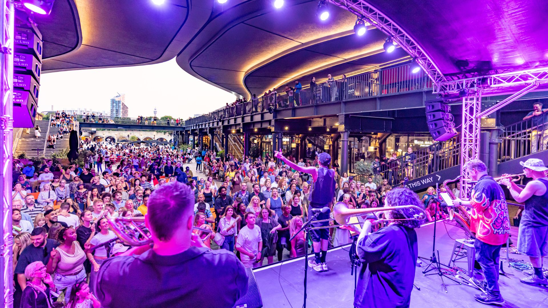 An image from 2025 Summer Sounds showing a band performing on stage in purple lights to a crowd 