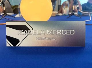 A name tag with a Superman logo reads Isabela Merced