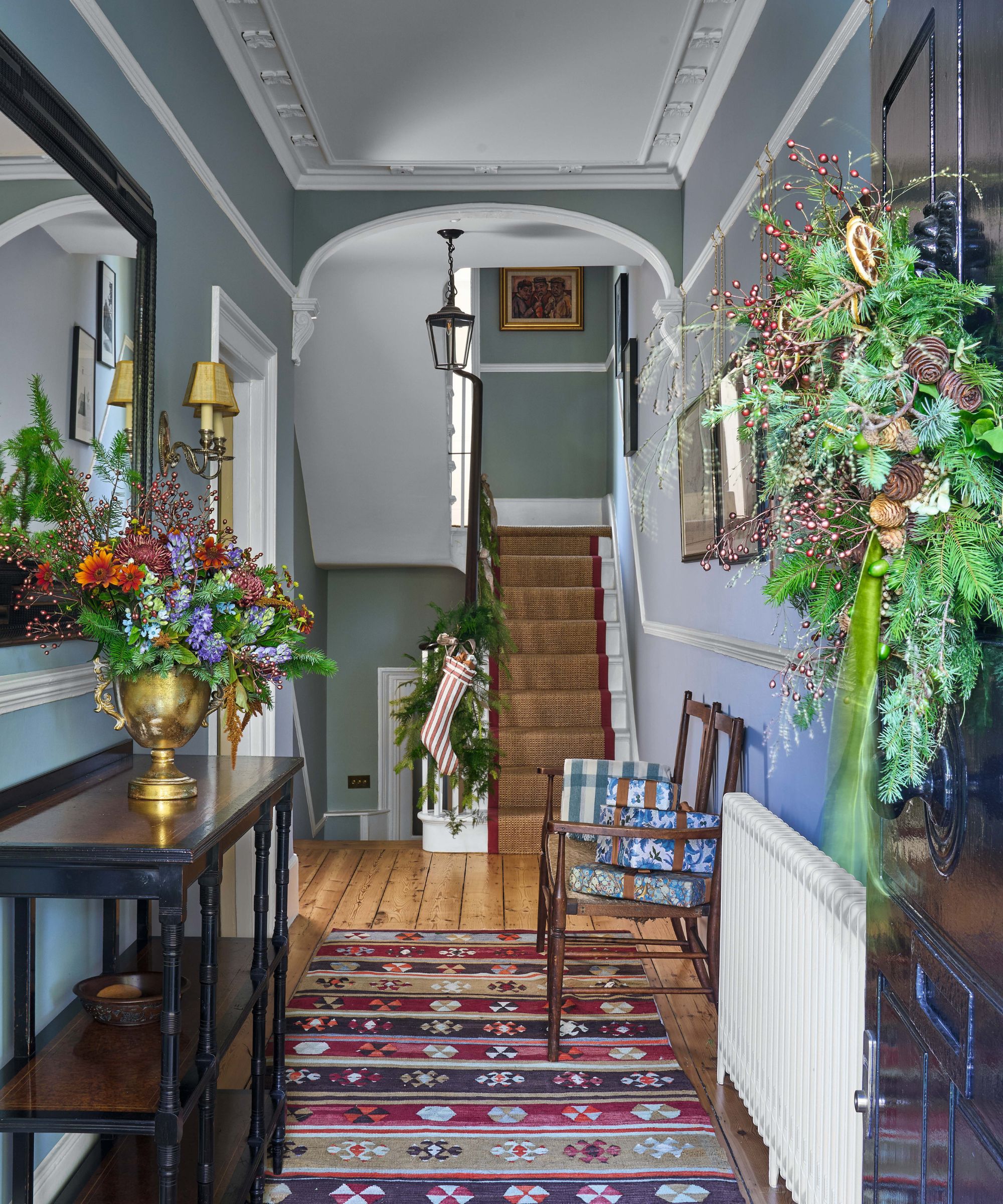 Elegant blue entryway decorated for Christmas with a console table and antique chair
