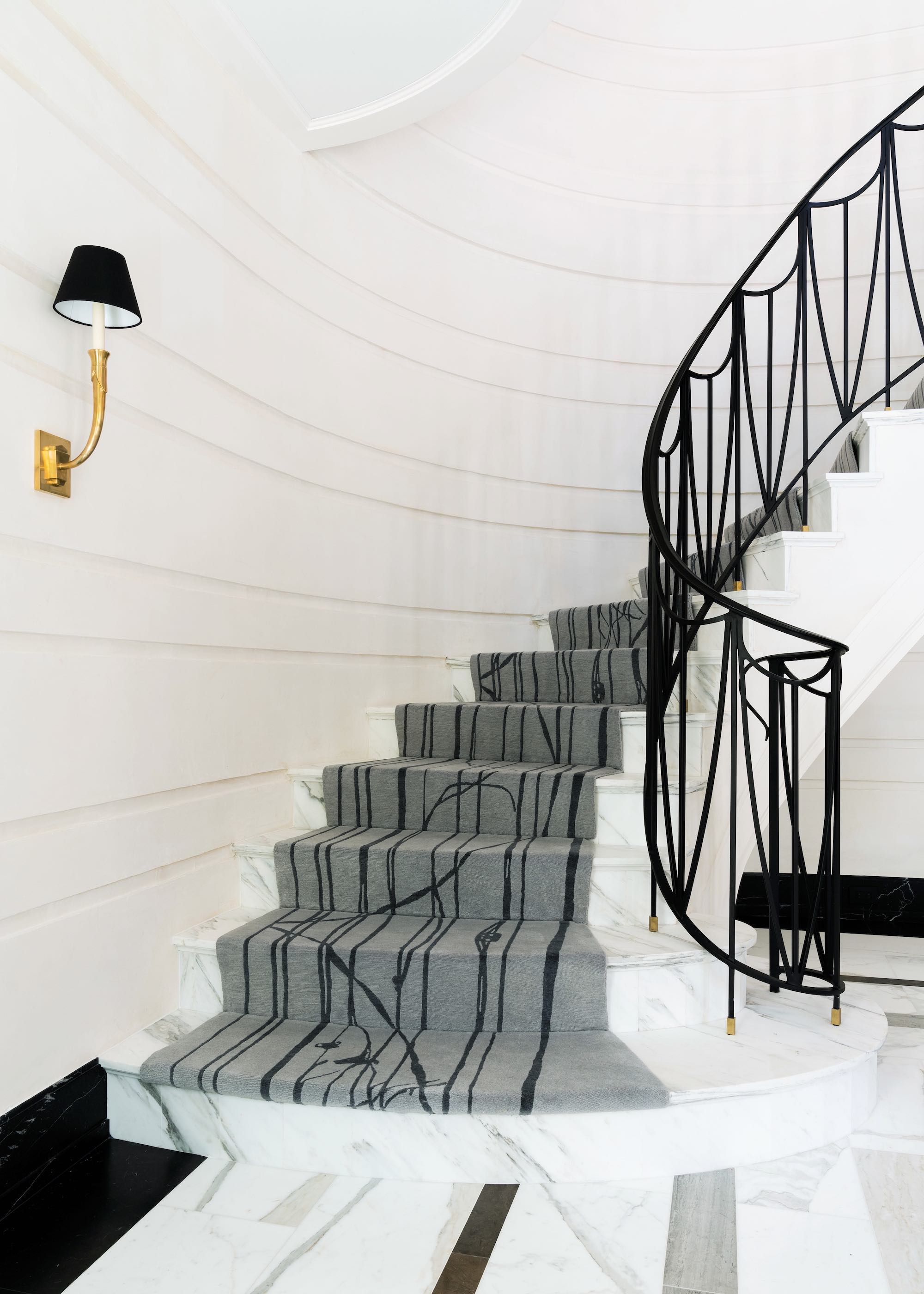 marble staircase with black spindles and grey abstract runner