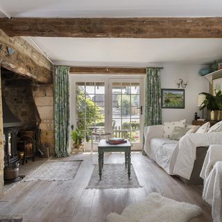 living room with wooden beams and floors and stone fireplace