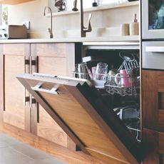 A wood-finish kitchen with an open, loaded dishwasher