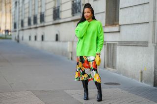 woman in neon green sweater, floral skirt, and black boots