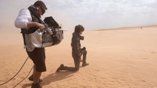 Greig Fraser filmar Timothée Chalamet som står på knä ute i en öken och blickar ut i fjärran.