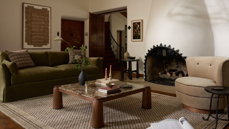 a cozy living room with a large fireplace, a wood and marble coffee table, a green couch, and a tan swivel chair
