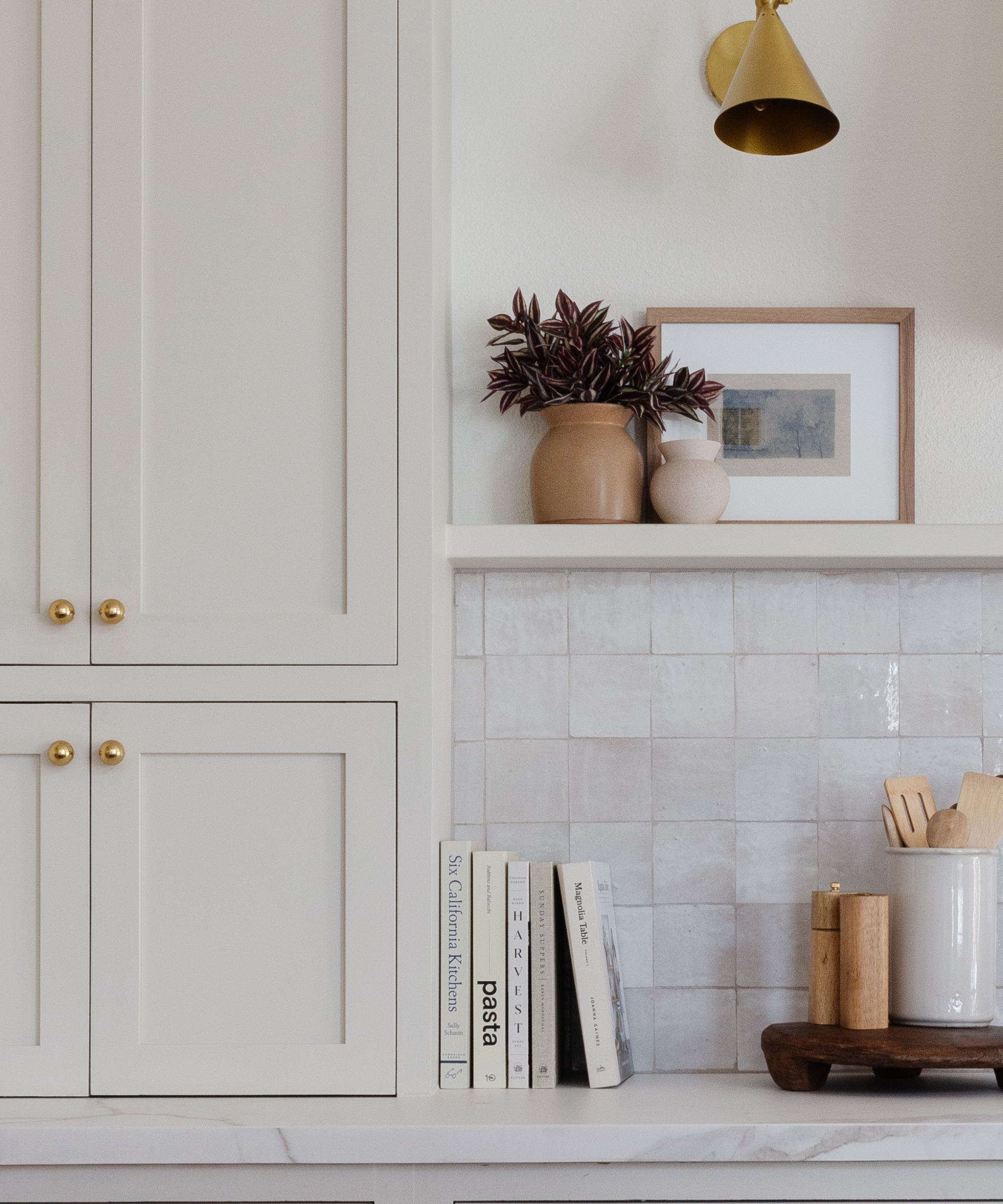 a kitchen countertop with a collection of books and a salt and pepper shaker and a jar of spoons on a wooden tray