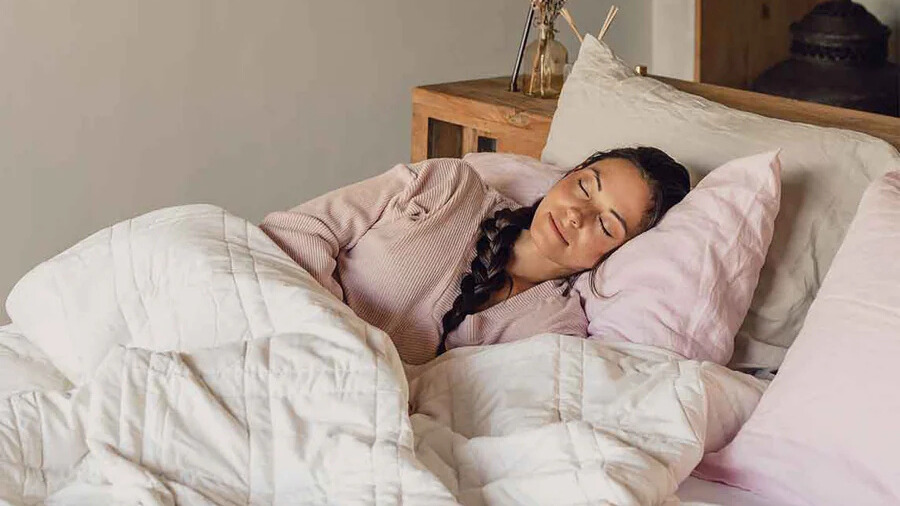 Woman sleeping in bed using a white Baloo weighted blanket
