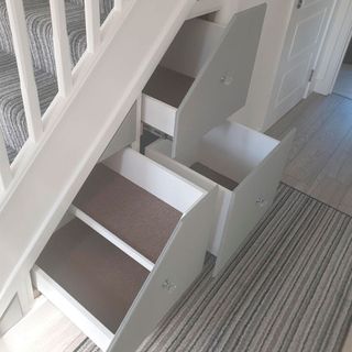white pull out drawers in under stairs storage area