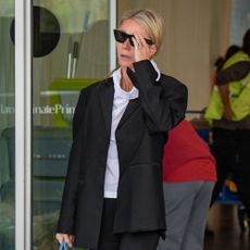 Gwyneth Paltrow steps out at Milan airport wearing loafers with capri pants and a black blazer.