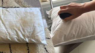 On the left, a pillow covered in yellow stains. On the right, a hand holding a soft bristled brush cleans a white pillow