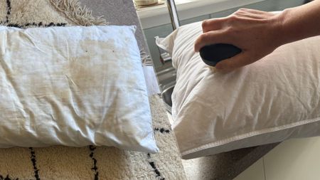 On the left, a pillow covered in yellow stains. On the right, a hand holding a soft bristled brush cleans a white pillow