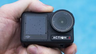 DJI Osmo Action 4 camera in the hand with swimming pool background