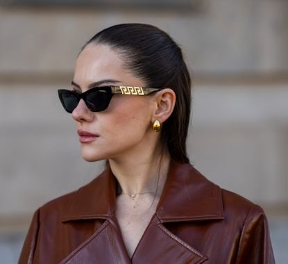 Berna Bilbey wears brown leather trench coat and oversized sunglasses