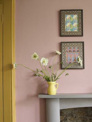 grey painted mantel with pink wall, artwork hung above, yellow jug with scabious, yellow woodwork on left side