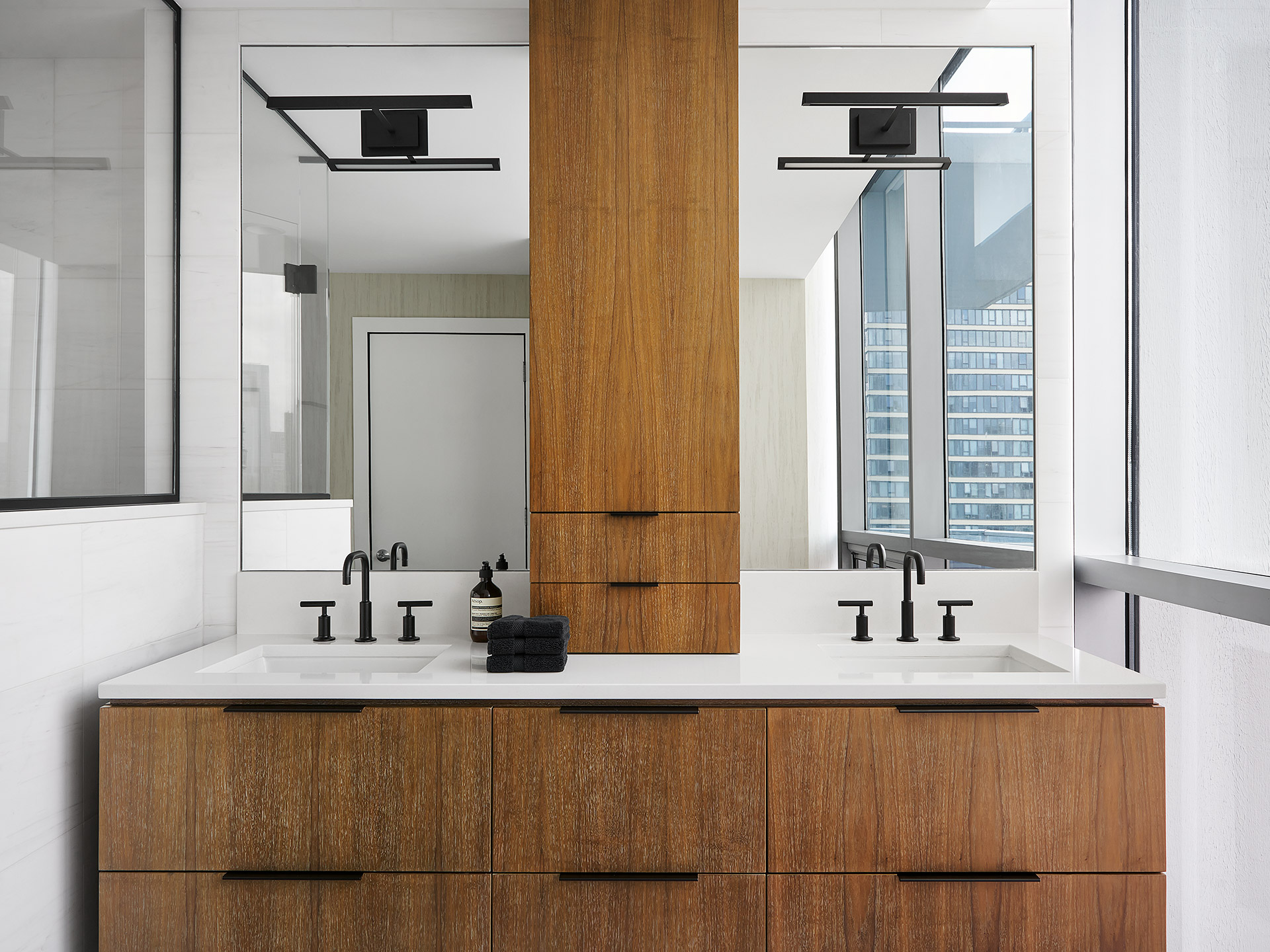 A modern white bathroom with a warm oak vanity unit and double sinks and mirrors.