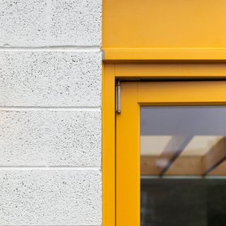 yellow painted door frame against a white brick wall