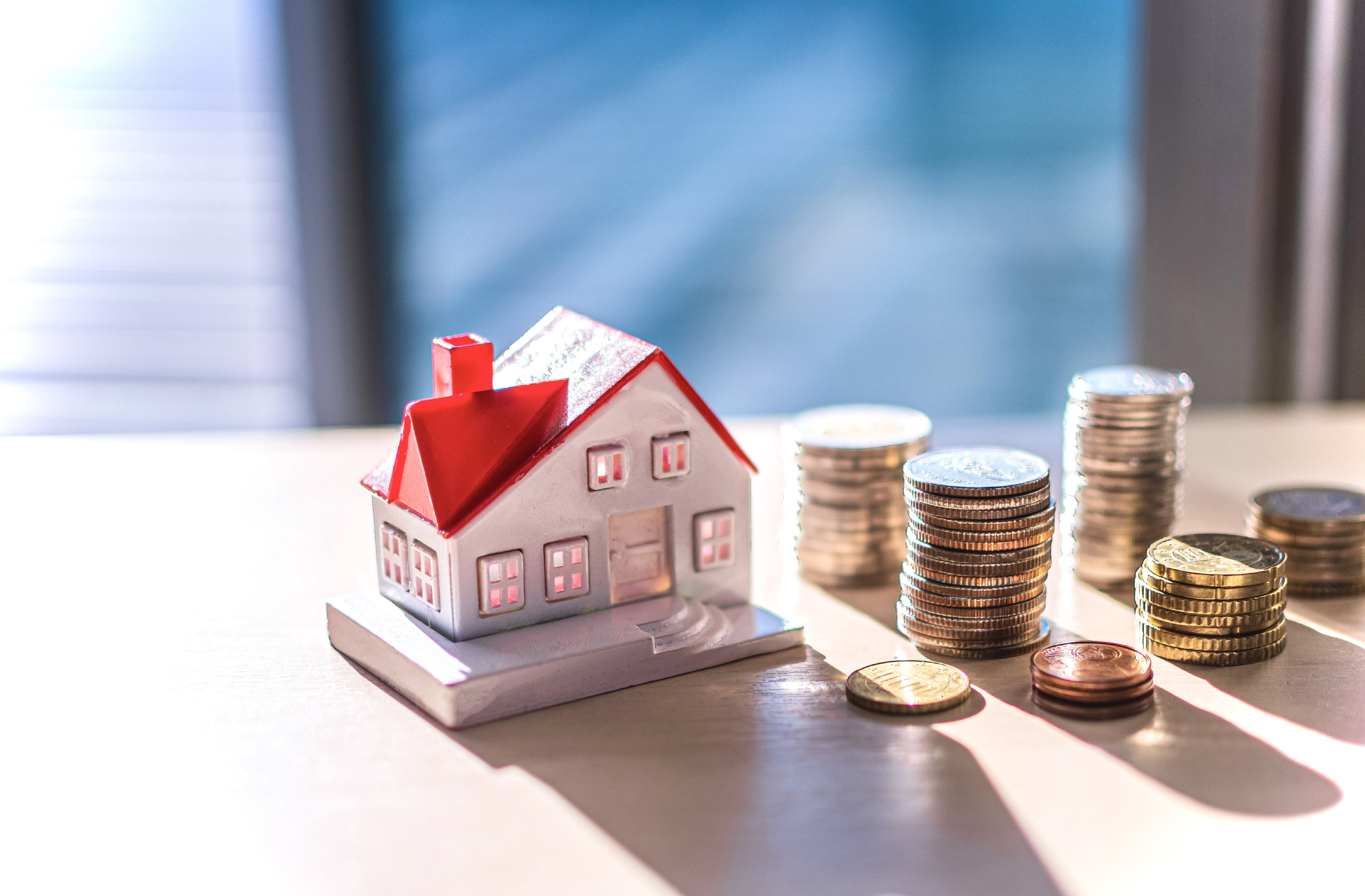 Wooden house model next to coins