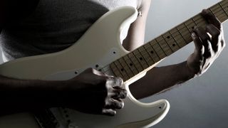 Guitarist playing Stratocaster on grey background