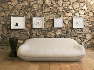 White sofa against a stone wall in Jorge Zalszupin's Sao Paulo house, now Casa Museo Zalszupin