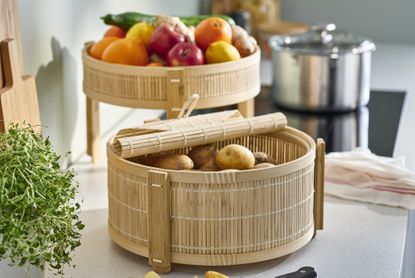  IKEA food storage basket. Bamboo basket semi open on a kitchen counter top with potatoes inside