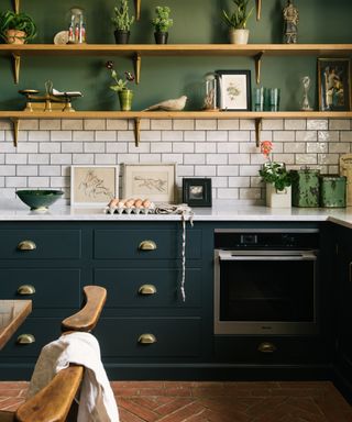 should I use handles or knobs on kitchen cabinets, two tone green kitchen, white metro tile backsplash, white countertop, brass handles, tiled terracotta floor