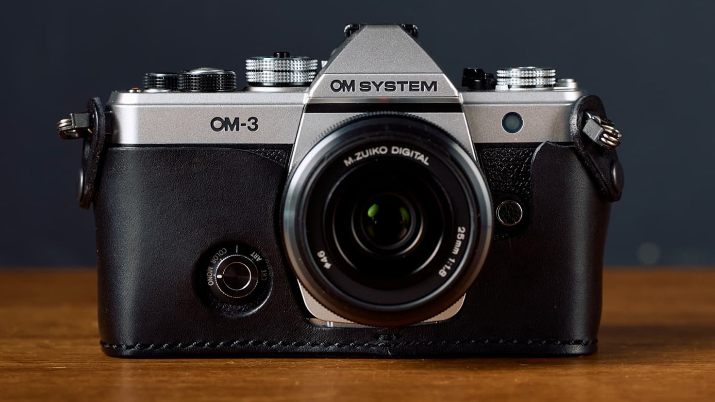 ROBERU OM-3 genuine leather holder & LeonCS strap set and OM System OM-3 lifestyle image on a blue background