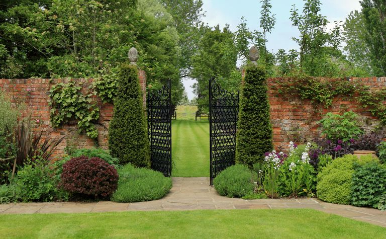 Lawn in garden with brick wall and gates