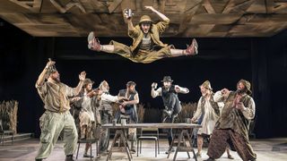 A scene from the musical 'Fiddler on the Roof' with a man leaping in a split. 