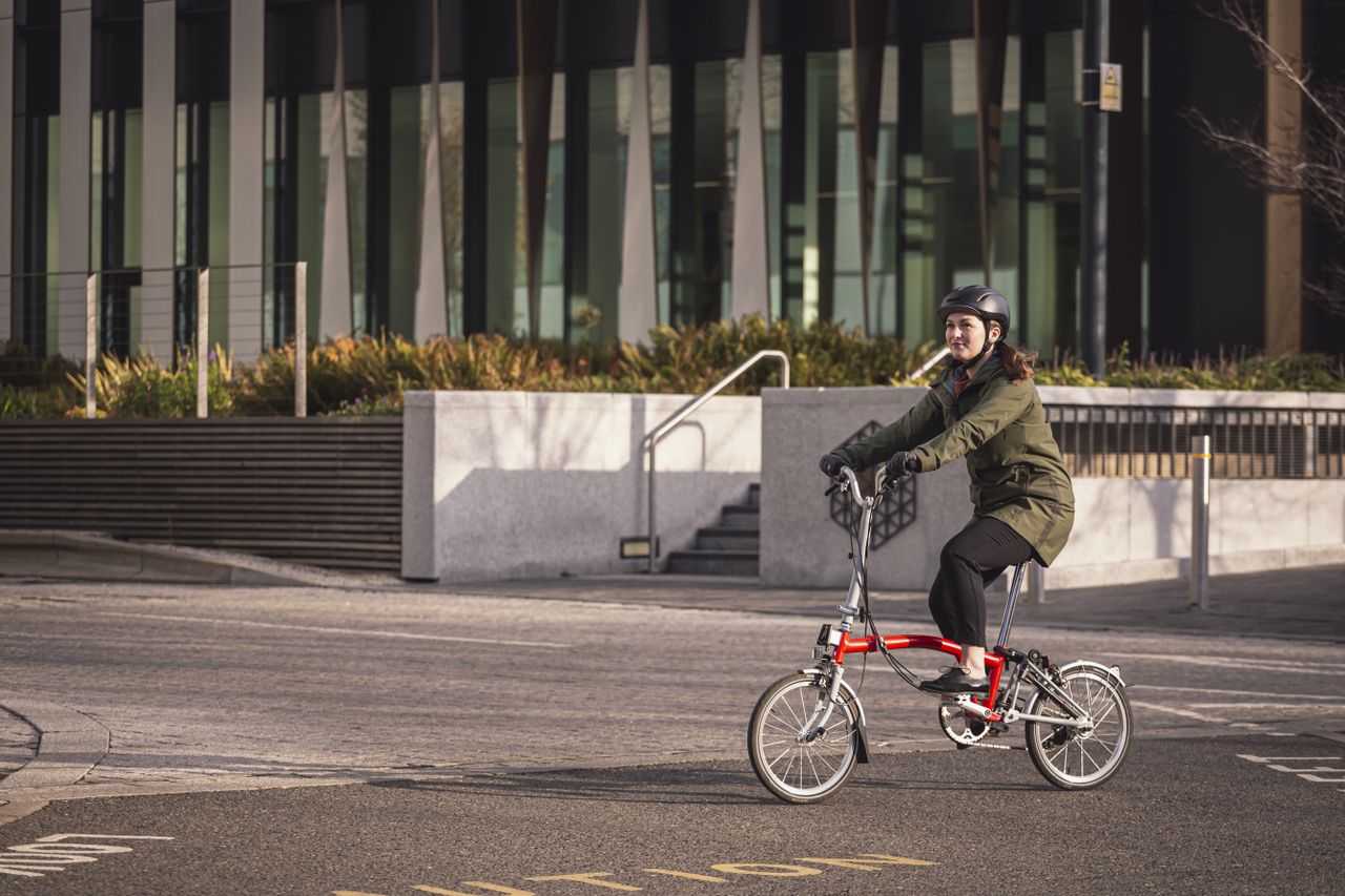 Female commuter riding a Brompton in Altura Grid Parka