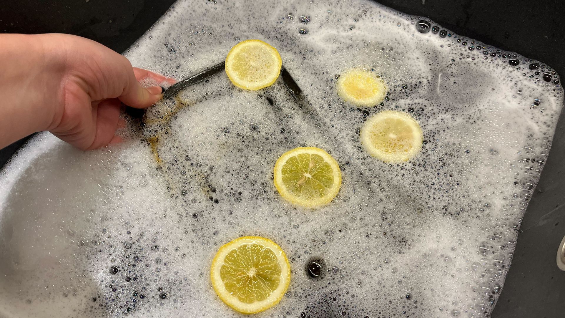 picture of soapy water with lemon slices and an air fryer grate being cleaned
