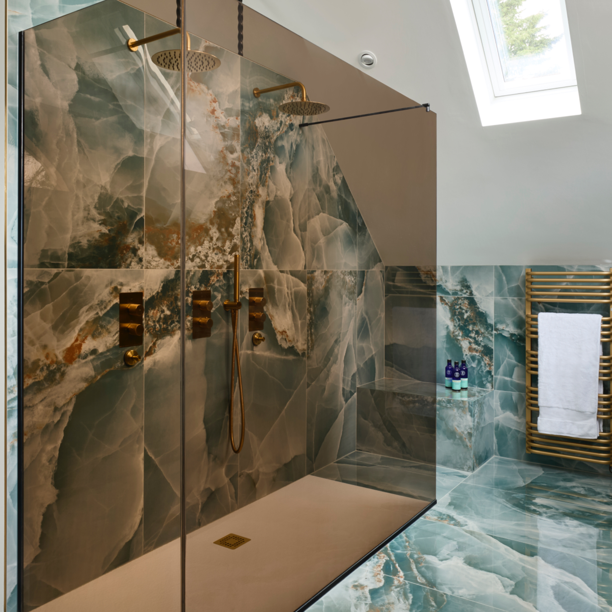 Walk in shower with tinted glass screens, marble tiles, towel radiator