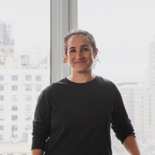Image of a woman in a black long sleeve shirt standing in front of a window.