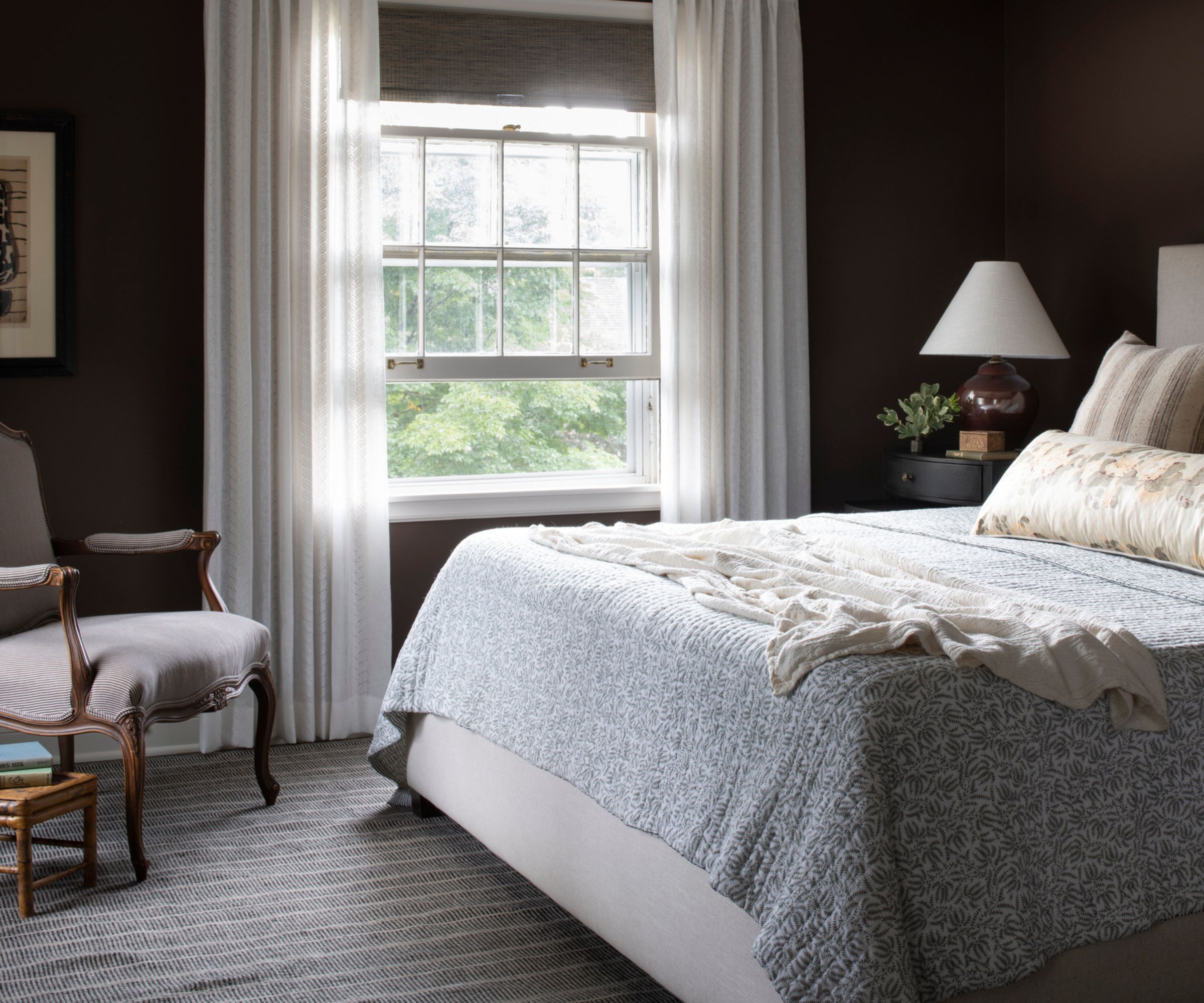 chocolate brown painted bedroom with a vintage style, large window, floral vintage bedspread and antique corner chair
