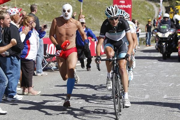 A masked fan runs alongside Andy Schleck as he leads Maxim Iglinksy (Astana) and Nicolas Roche (AG2R)