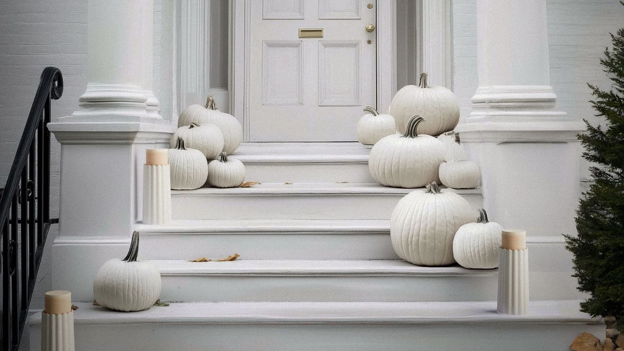 A front doorway with white pumpkin decor