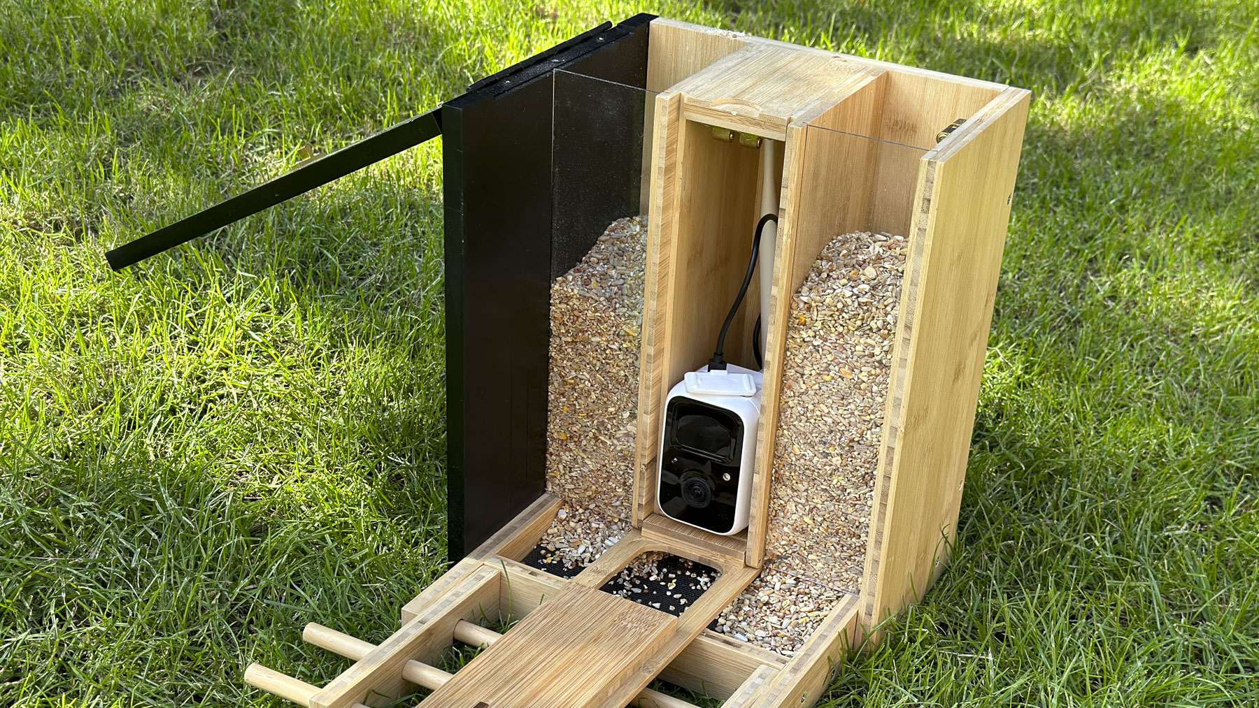 Netvue Birdfy Bamboo bird feeder camera outside on the grass with seed cover removed