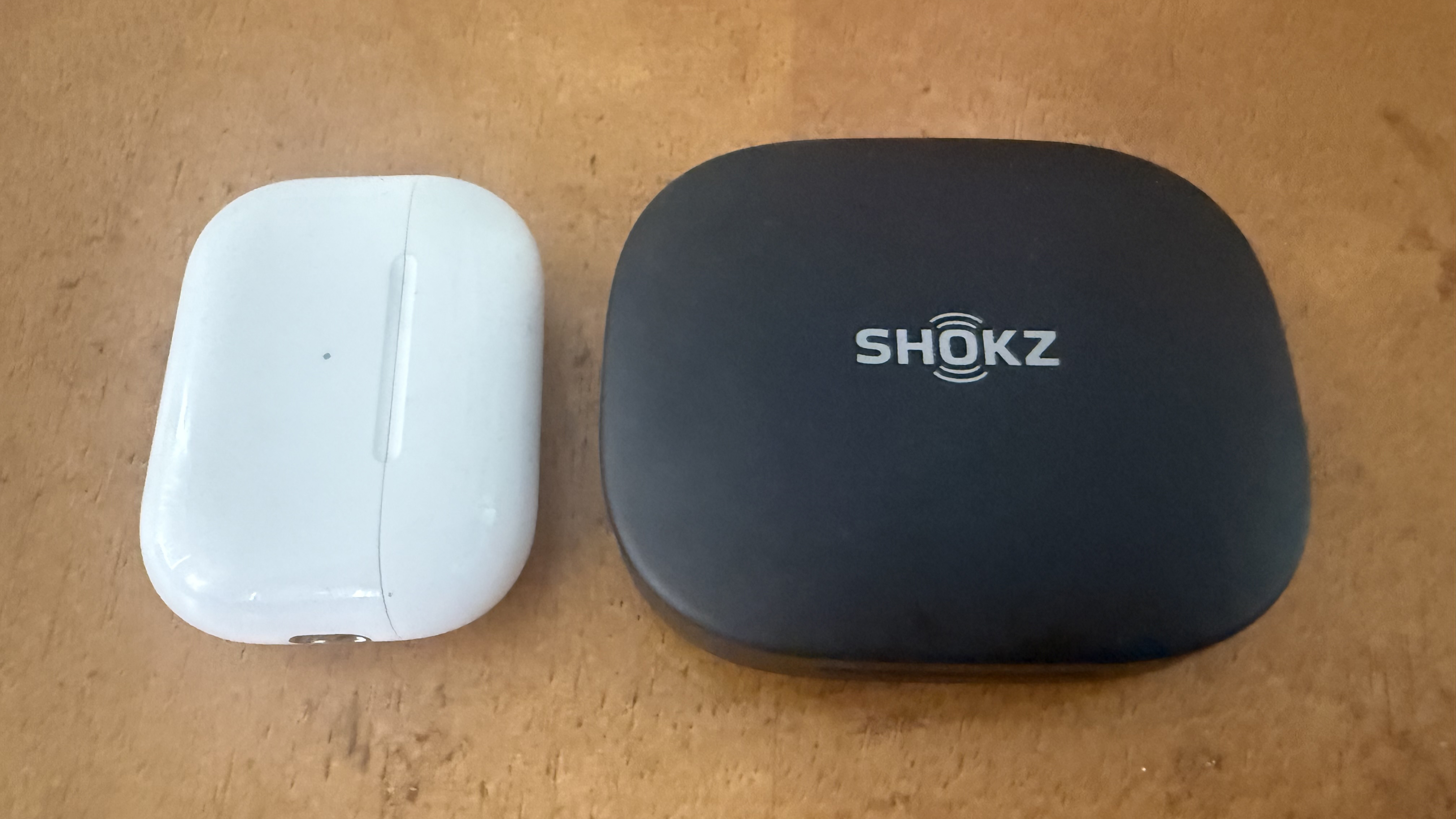 The Shokz OpenFit Pro charging case compared to the Apple AirPods Pro 2 case