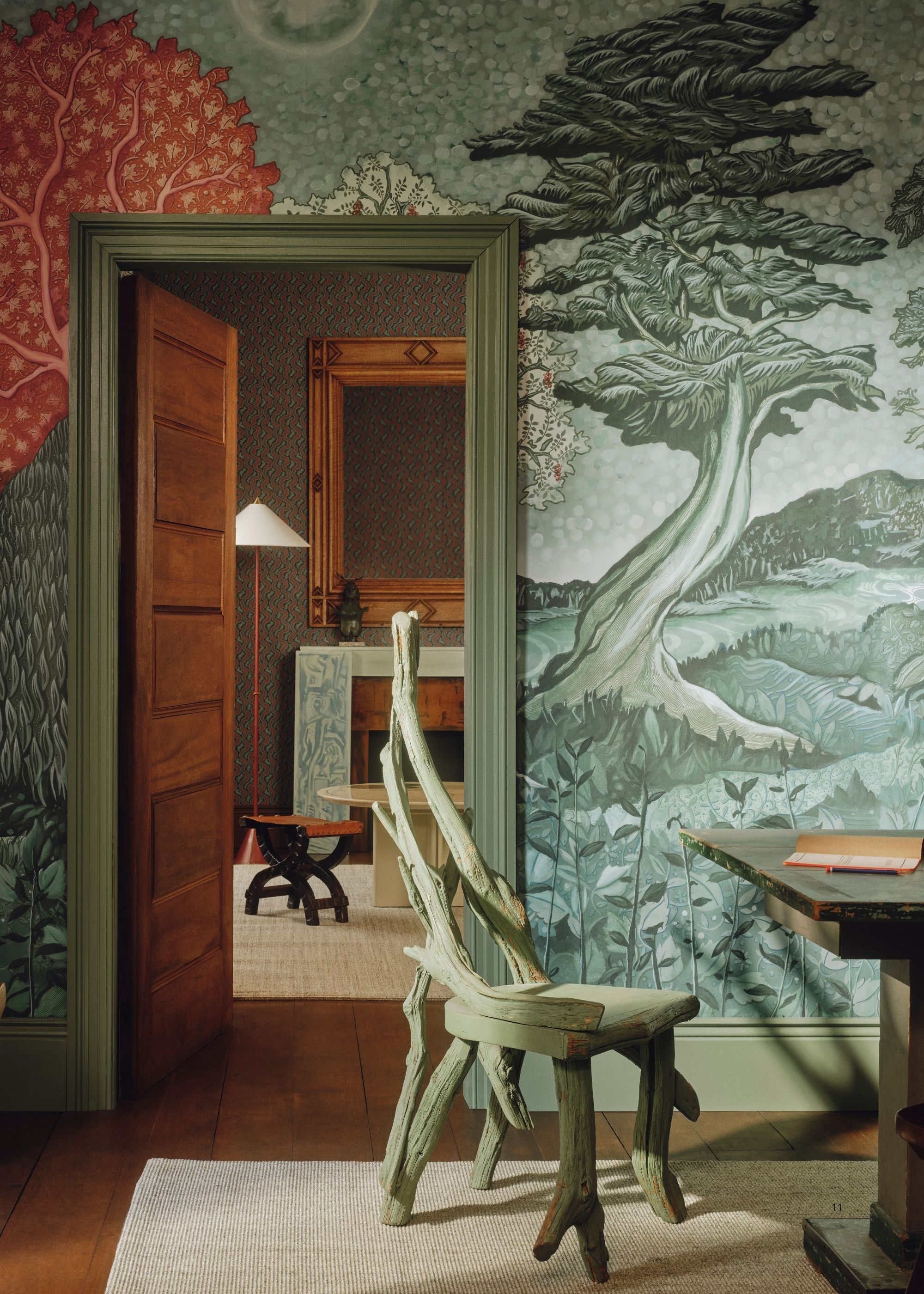 Image of a home office room with the door open to a living room. The trim is painted a seafoam green and there is a teal and green mural wallpaper on the walls.