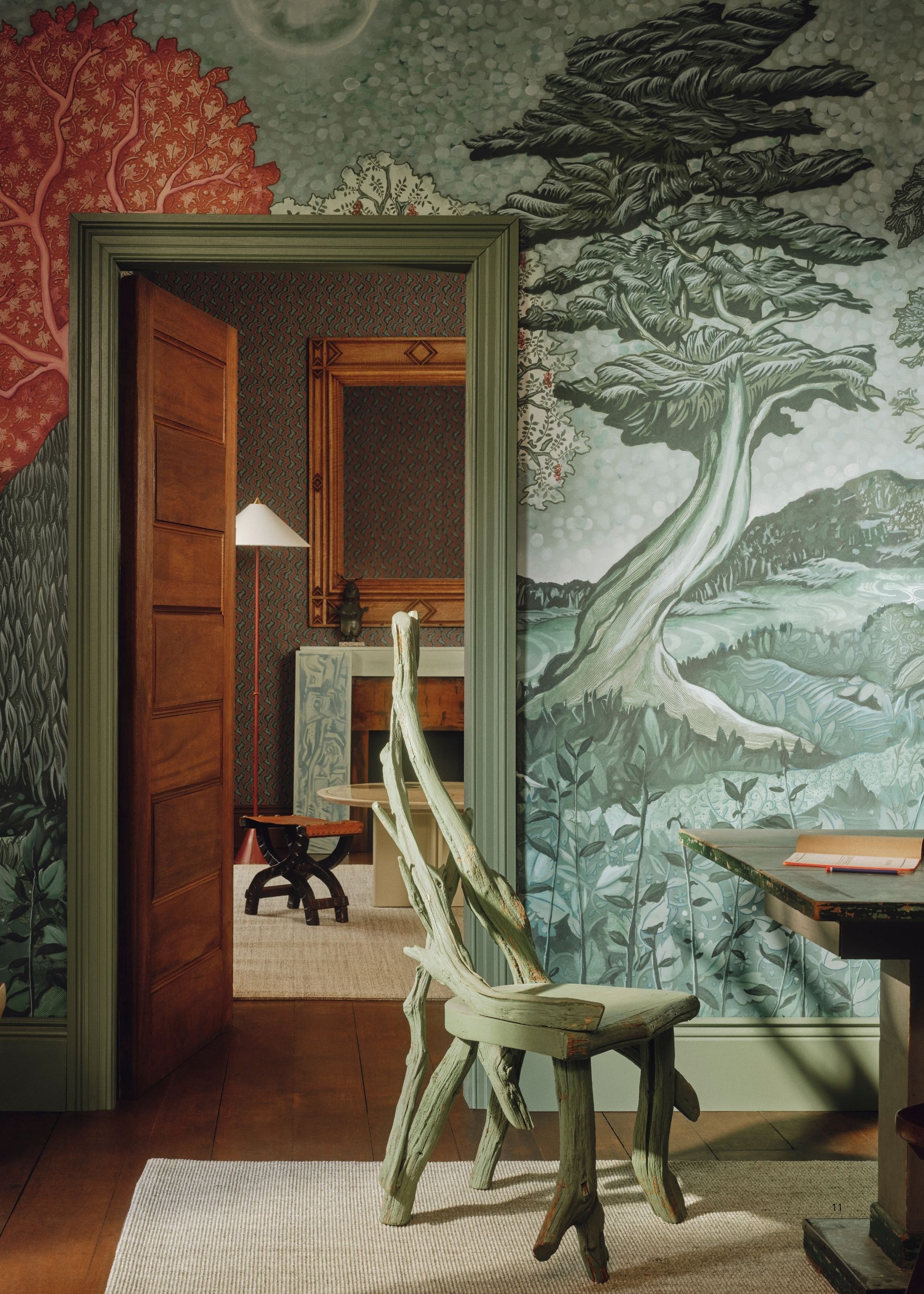 Image of a home office room with the door open to a living room. The trim is painted a seafoam green and there is a teal and green mural wallpaper on the walls.
