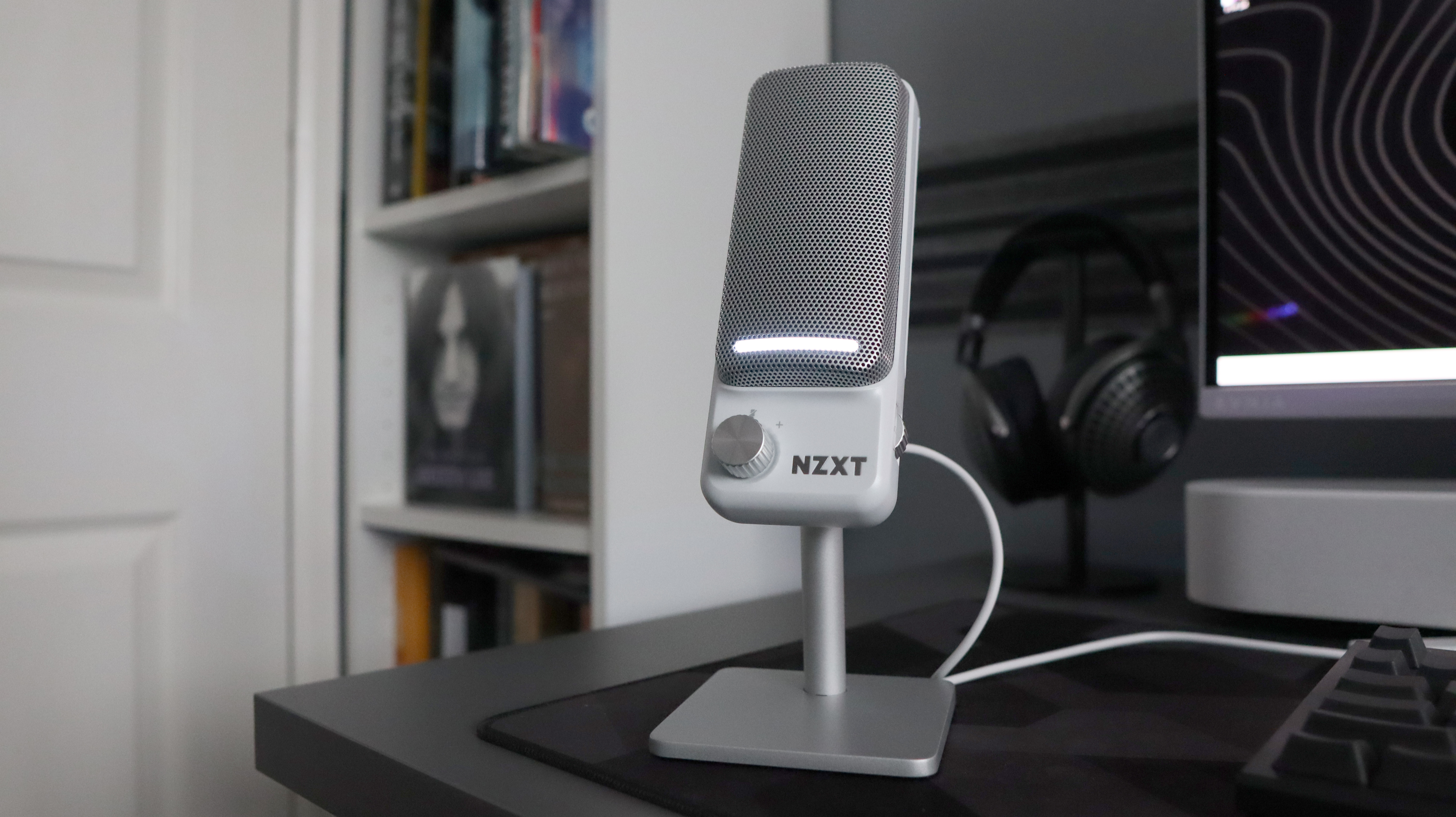 An NZXT Capsule Elite microphone set up on a desk with lighting enabled.