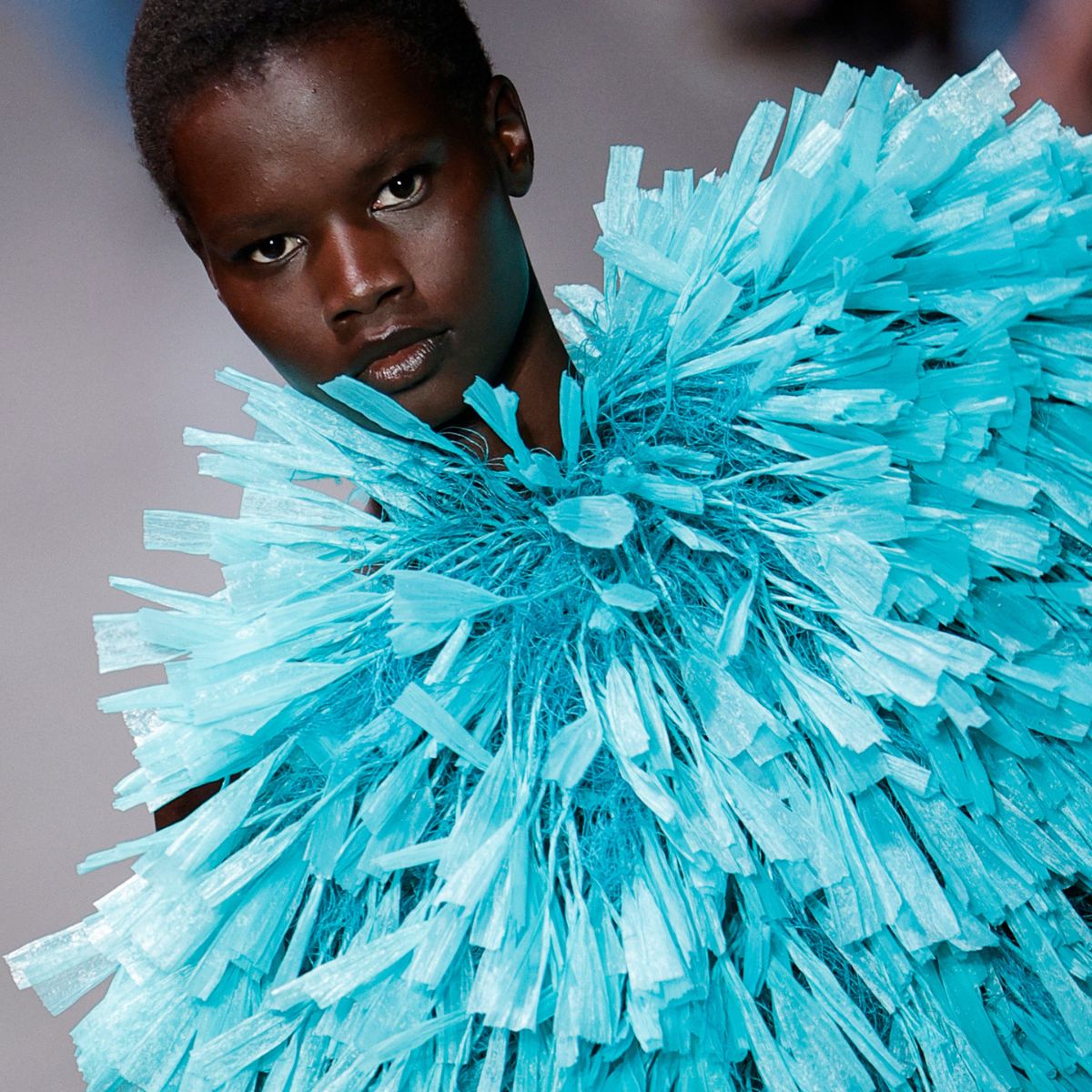 a model wearing a blue feathered top at the stella mccartney ss26 show